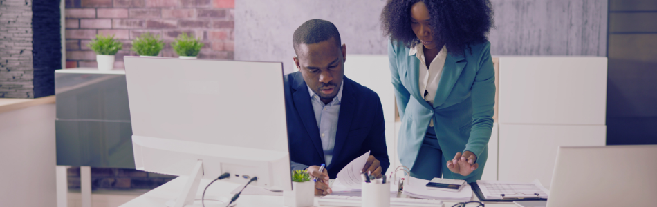 two people looking in a corporate setting looking a desktop computer