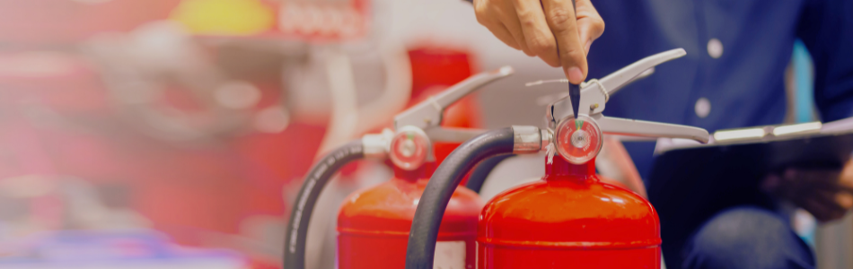 person with a clipboard in the background with red fire extinguishers in the foreground