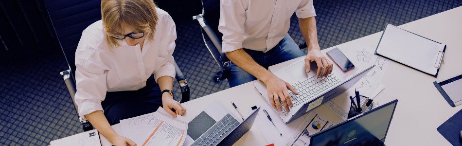 People working at a desk with a laptop and documents