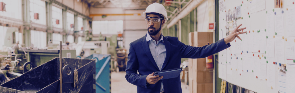 Man in a suit pointing at a whiteboard on a construction site