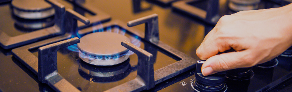 person turning on a gas stove cooktop